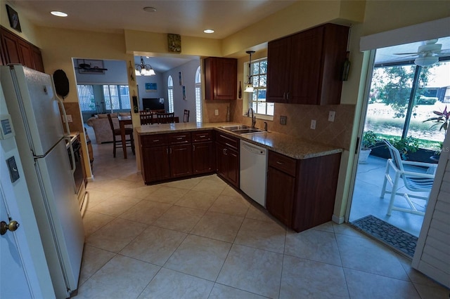 kitchen with sink, decorative light fixtures, white appliances, decorative backsplash, and ceiling fan with notable chandelier