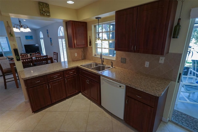 kitchen featuring kitchen peninsula, white dishwasher, sink, pendant lighting, and a chandelier