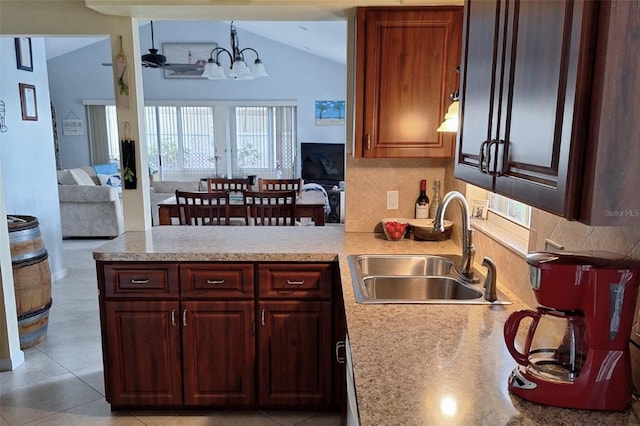 kitchen featuring decorative backsplash, sink, decorative light fixtures, a chandelier, and lofted ceiling