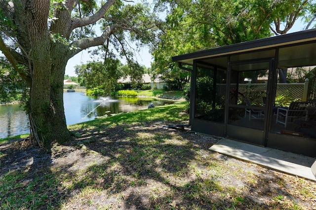 view of yard with a sunroom and a water view