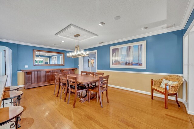 dining area featuring crown molding, light wood-type flooring, and a textured ceiling