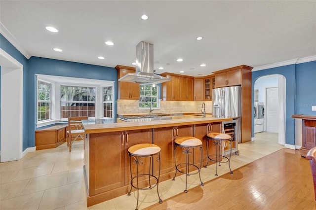 279 Rippling Ln, Winter Park, FL 32789 - kitchen with island exhaust hood, arched walkways, wine cooler, light countertops, and backsplash