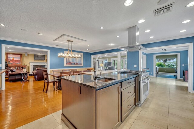 kitchen featuring a center island with sink, island exhaust hood, stainless steel range, and a textured ceiling