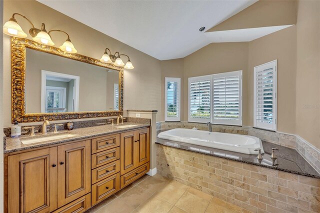 bathroom featuring tile patterned floors, tiled tub, vanity, and lofted ceiling