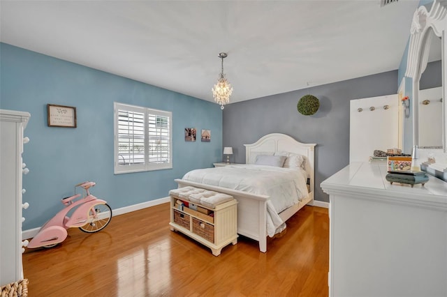 bedroom featuring wood-type flooring and a notable chandelier