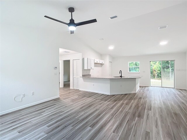 interior space with kitchen peninsula, light hardwood / wood-style flooring, white cabinetry, ceiling fan, and sink