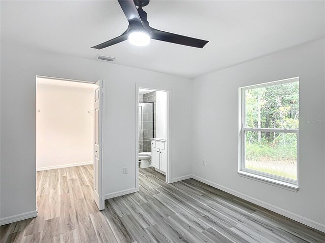 unfurnished bedroom with connected bathroom, ceiling fan, and light hardwood / wood-style floors