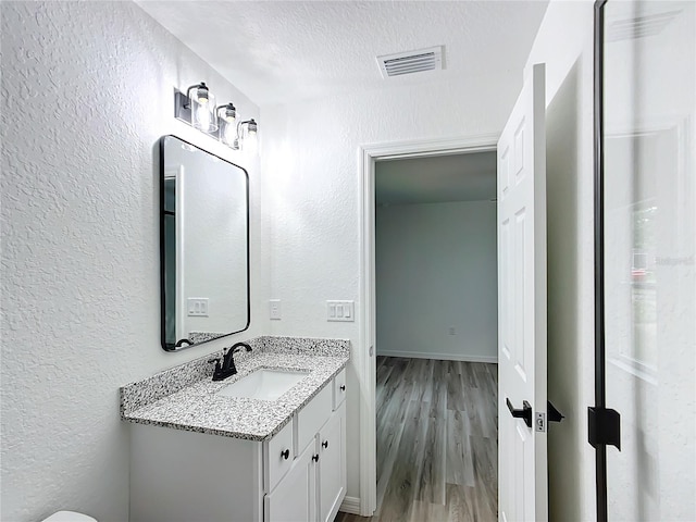 bathroom featuring a textured ceiling, wood-type flooring, and vanity