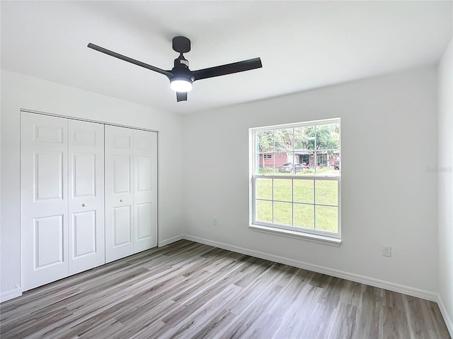 unfurnished bedroom with ceiling fan, light hardwood / wood-style flooring, and a closet