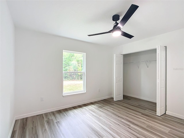 unfurnished bedroom featuring ceiling fan, light hardwood / wood-style floors, and a closet