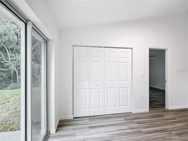 unfurnished bedroom featuring a closet, light hardwood / wood-style floors, and multiple windows