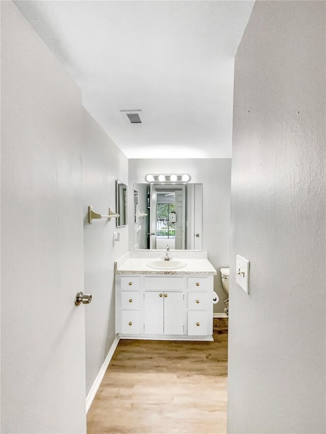 bathroom featuring wood-type flooring, vanity, and toilet