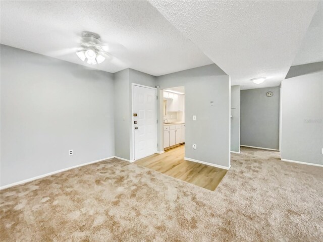 unfurnished room featuring ceiling fan, a textured ceiling, and light colored carpet