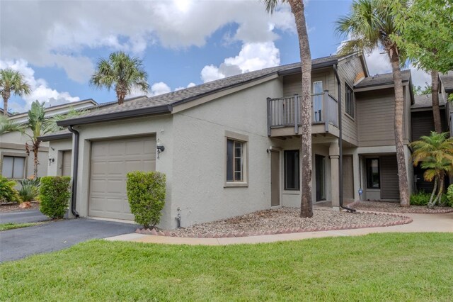 view of front of property featuring a balcony, a garage, and a front yard