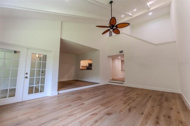 unfurnished room featuring ceiling fan, light hardwood / wood-style flooring, a high ceiling, and french doors