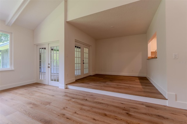 foyer with lofted ceiling with beams, french doors, light wood-style flooring, and baseboards