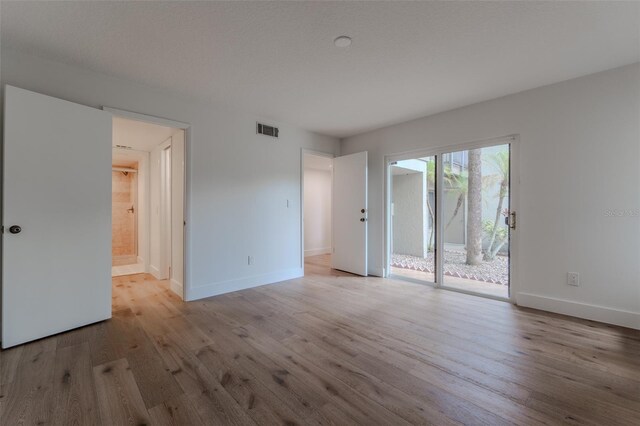 unfurnished bedroom featuring access to outside, hardwood / wood-style flooring, and ensuite bathroom