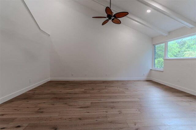 empty room with ceiling fan, high vaulted ceiling, wood finished floors, baseboards, and beam ceiling