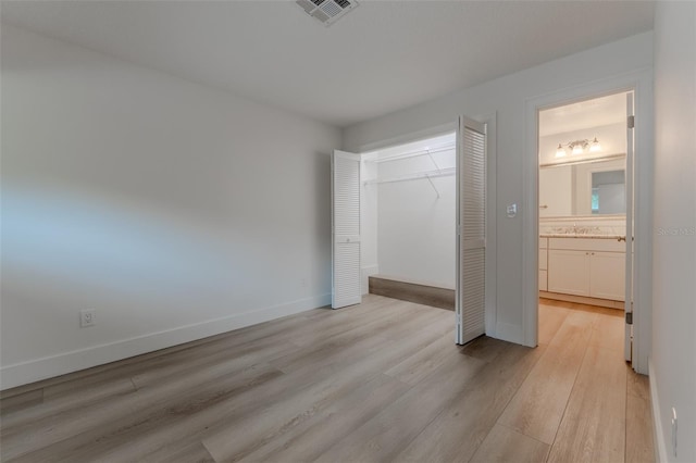 unfurnished bedroom featuring a closet, light hardwood / wood-style floors, and ensuite bathroom