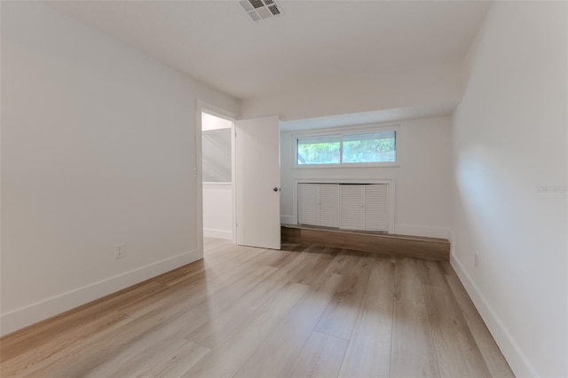 unfurnished room featuring light wood-style flooring, visible vents, and baseboards