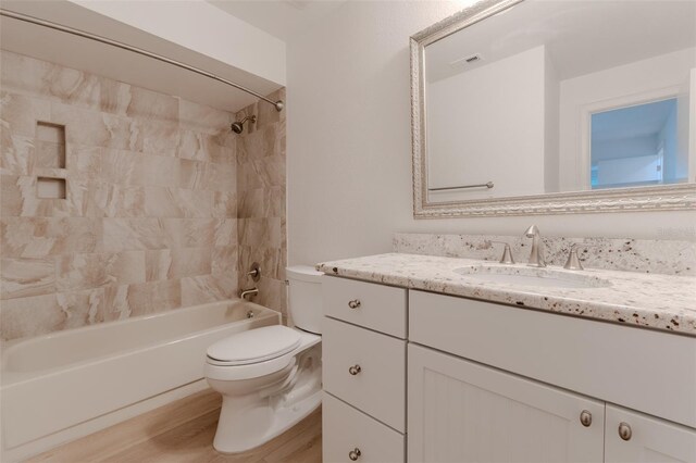 bathroom featuring visible vents, toilet, shower / bathtub combination, wood finished floors, and vanity