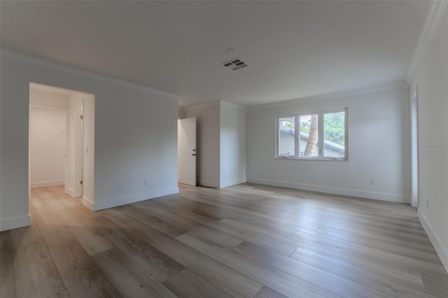 spare room featuring light wood-type flooring, baseboards, visible vents, and crown molding