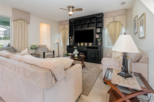 living room featuring built in features, light tile patterned floors, and ceiling fan