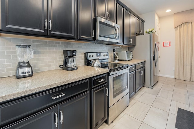 kitchen with light tile patterned floors, stainless steel appliances, light stone counters, and backsplash