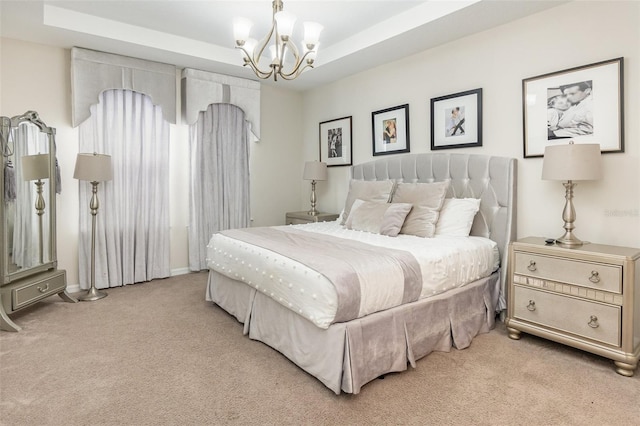 carpeted bedroom featuring a notable chandelier and a tray ceiling