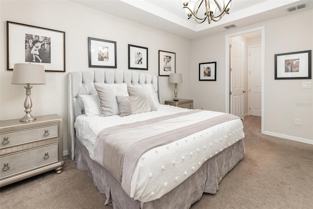 carpeted bedroom featuring an inviting chandelier and a tray ceiling