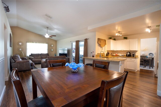 dining area with sink, dark wood-type flooring, ceiling fan, and vaulted ceiling