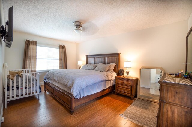 bedroom with ceiling fan, a textured ceiling, and hardwood / wood-style flooring