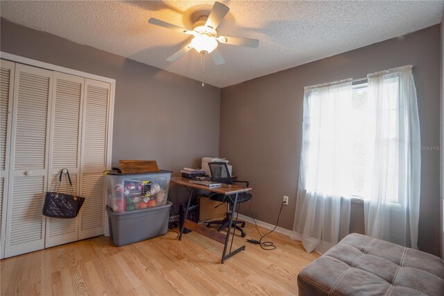 home office with a textured ceiling, ceiling fan, and light wood-type flooring