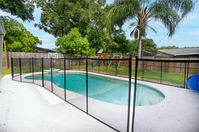 view of swimming pool featuring a patio, a yard, and a playground