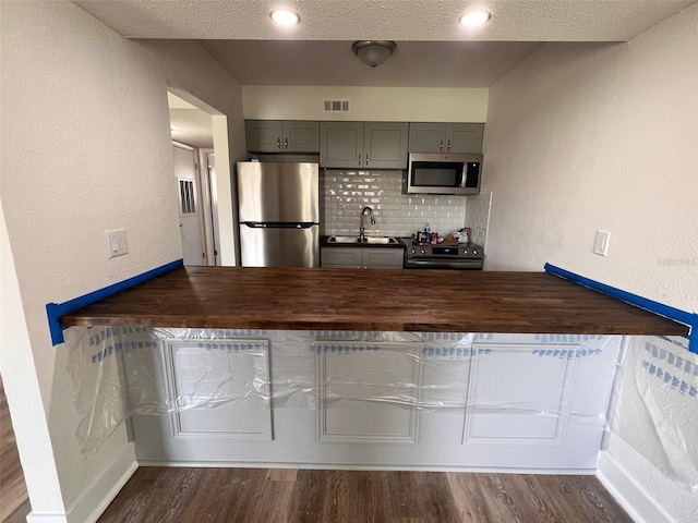 kitchen with decorative backsplash, dark hardwood / wood-style flooring, appliances with stainless steel finishes, and gray cabinetry