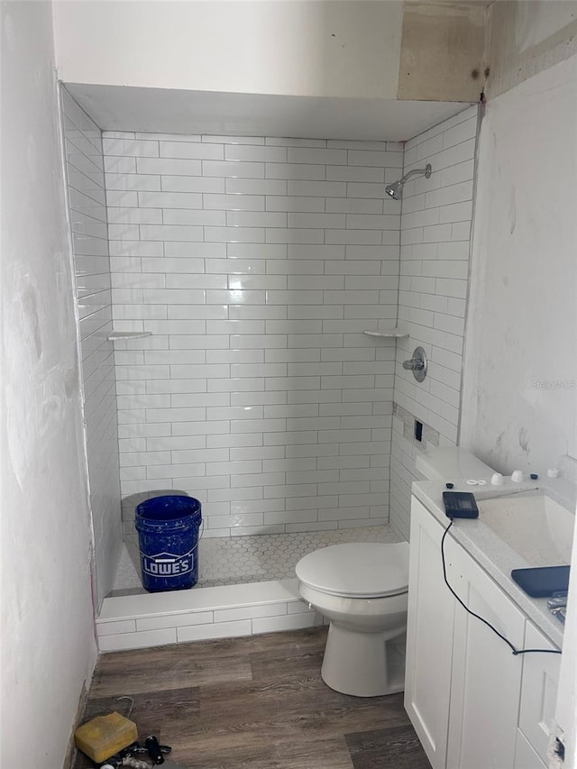 bathroom with toilet, a stall shower, wood finished floors, and vanity