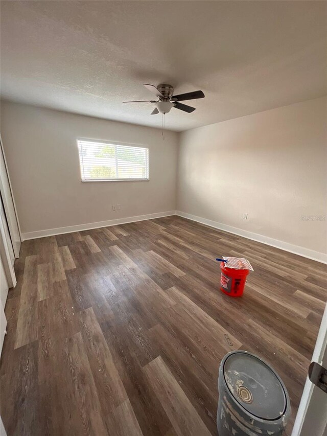 empty room with ceiling fan and dark wood-type flooring