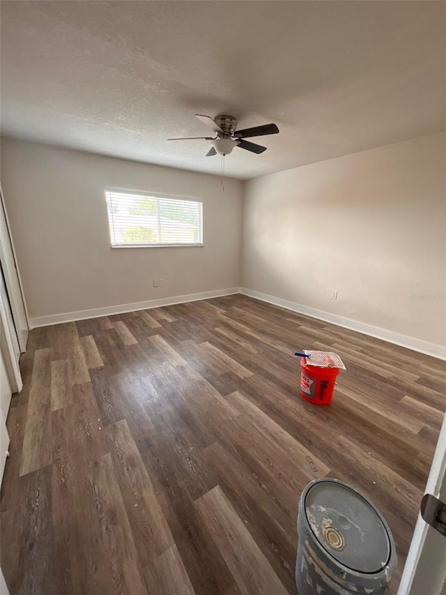 unfurnished room featuring a ceiling fan, dark wood finished floors, a textured ceiling, and baseboards