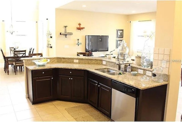 kitchen with sink, light stone counters, light tile patterned floors, and stainless steel dishwasher