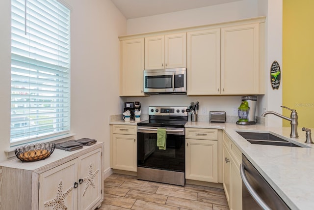 kitchen with light hardwood / wood-style floors, cream cabinets, stainless steel appliances, and sink