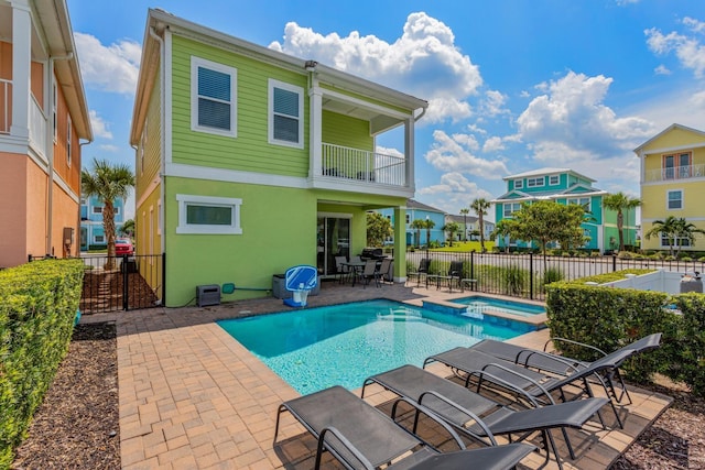 back of property with a swimming pool with hot tub, a patio, and a balcony