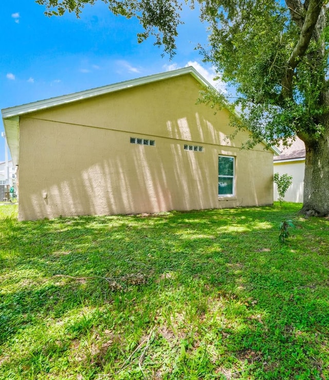 view of side of property featuring a lawn and stucco siding