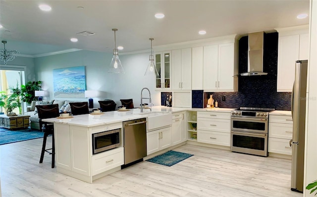 kitchen with a sink, visible vents, open floor plan, appliances with stainless steel finishes, and wall chimney exhaust hood