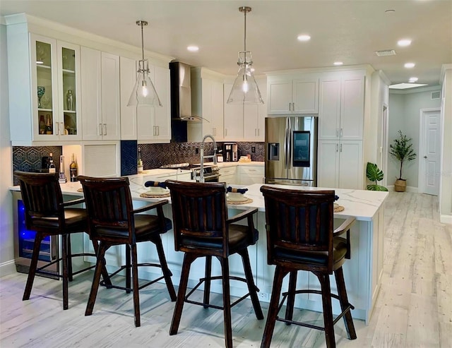 kitchen with stainless steel appliances, a peninsula, visible vents, wall chimney exhaust hood, and tasteful backsplash