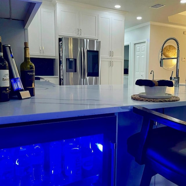 kitchen featuring white cabinets, crown molding, visible vents, and stainless steel fridge with ice dispenser