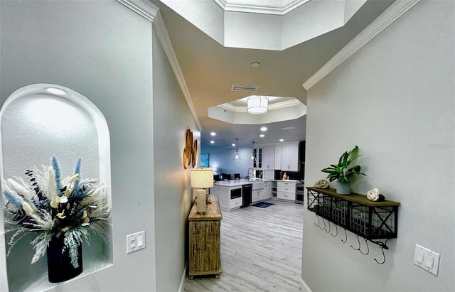 hallway with visible vents, a raised ceiling, light wood-style flooring, crown molding, and recessed lighting