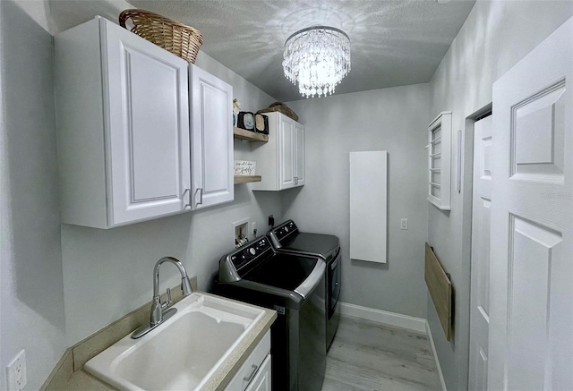 laundry area featuring a sink, baseboards, cabinet space, washer and clothes dryer, and an inviting chandelier