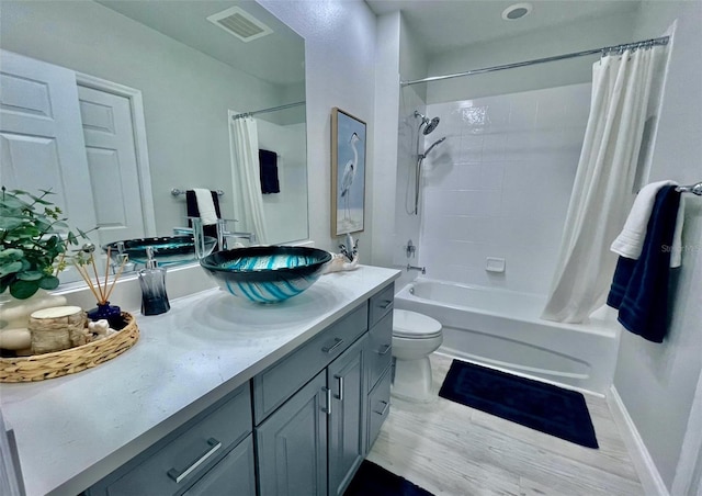 bathroom with toilet, visible vents, vanity, baseboards, and shower / bath combo with shower curtain