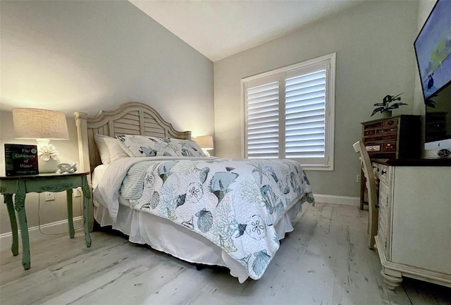 bedroom featuring light wood-style floors, baseboards, and vaulted ceiling