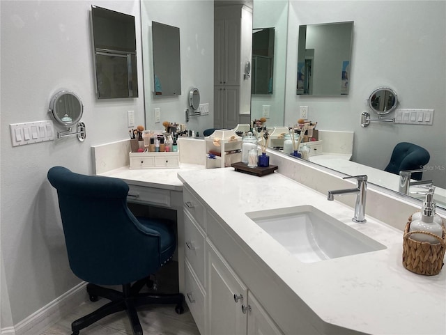 bathroom featuring a shower with door, baseboards, and vanity